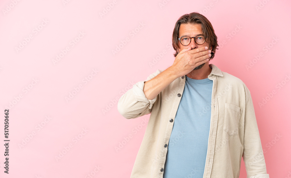 Senior dutch man isolated on pink background covering mouth with hand