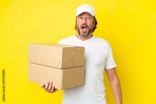 Delivery senior dutch man isolated on yellow background with surprise facial expression