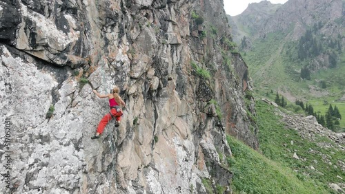 Woman athlette climbing on the high rock in the mountains photo