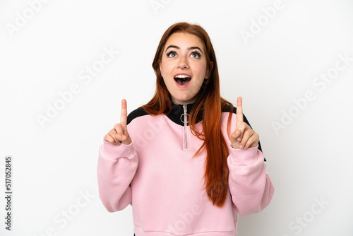 Young redhead woman isolated on white background surprised and pointing up