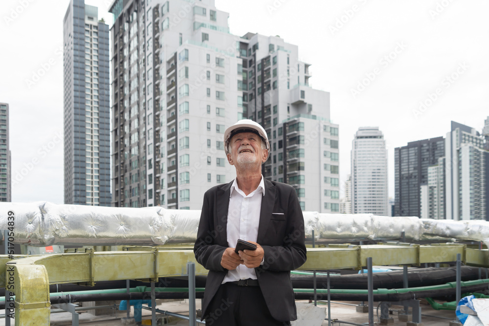 An old elderly engineer man or worker, people working in industry factory, using a mobile phone technology device. Chiller tower on rooftop building. System work machine. Condenser pipe lines. An old elderly engineer man or worker, people working in industry factory, using a mobile phone technology device. Chiller tower on rooftop building. System work machine. Condenser pipe lines.