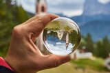 Photo through a glass ball. Church of San Giacomo. Ortisei, Gardena Valley, South Tyrol, Dolomites, Italy.