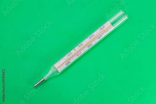 Mercury medical thermometer close-up on a green surface