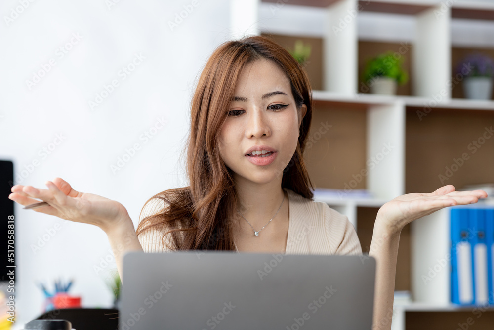 Beautiful Asian businesswoman sitting in her private office, she is talking to her partner via video call on her laptop, she is a female executive of a startup company. Concept of financial management Beautiful Asian businesswoman sitting in her private office, she is talking to her partner via video call on her laptop, she is a female executive of a startup company. Concept of financial management