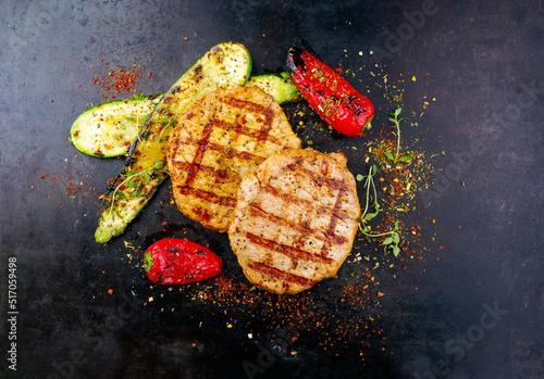 Traditionelle Putenschnitzel vom Grill in Curry Marinade mit gegrilltem Gemüse serviert als Draufsicht auf einem alten rustikalen Board mit Textfreiraum  photo