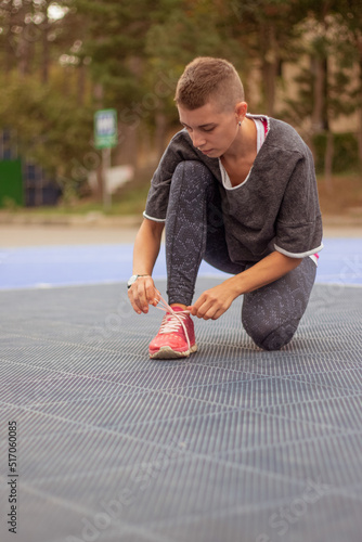 young woman with short hair in sportswear put on sneakers