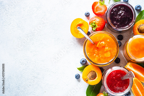 Fotografia Homemade jams, natural preservation in glass jars with ingredients, fresh fruits and berries