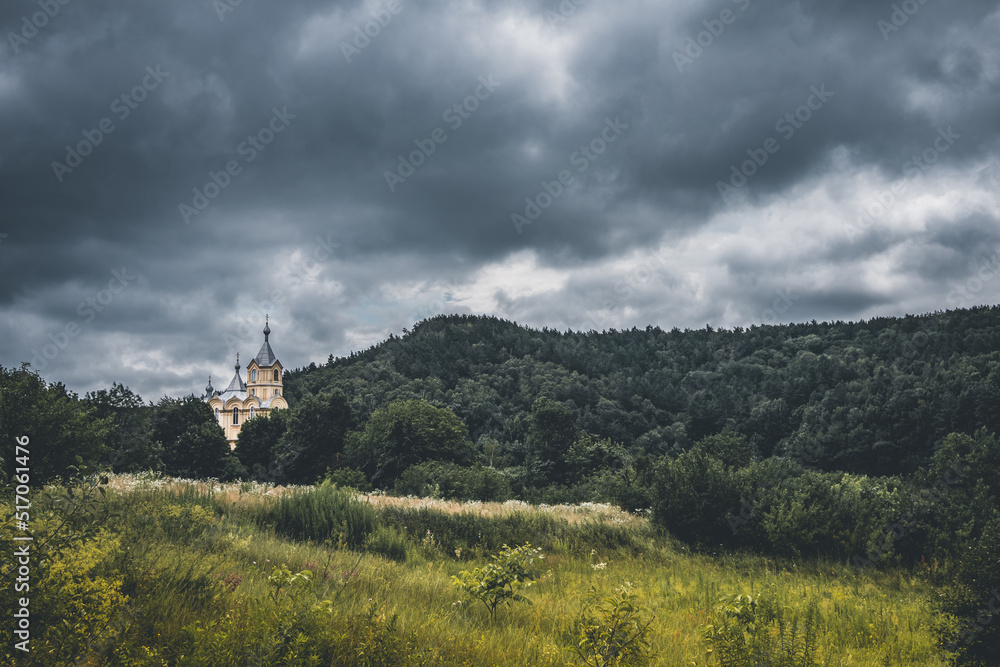 Cloudy summer mountain landscape in Ukraine. Typical small traditional ukrainian church in the mountains with deep forests and cloudy sky Cloudy summer mountain landscape in Ukraine. Typical small traditional ukrainian church in the mountains with deep forests and cloudy sky
