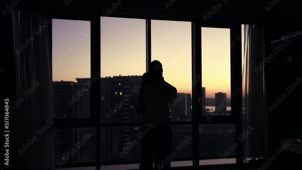 Silhouette of a guy hugging a girl against the backdrop of panoramic windows overlooking the city and sunset. Silhouette of a guy hugging a girl against the backdrop of panoramic windows overlooking the city and sunset.