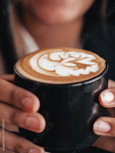 Coffee shop heart cream design on black mug in hands. Hot coffee espresso barista latte art. Relaxing space with coffee in hands 