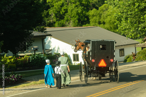 Amish family walking beside a family in a buggy photo