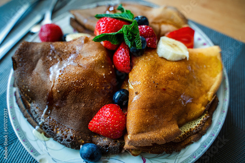 Healthy breakfast concept of crispy pancake with banana, strawberries and blueberry with honey spread on top