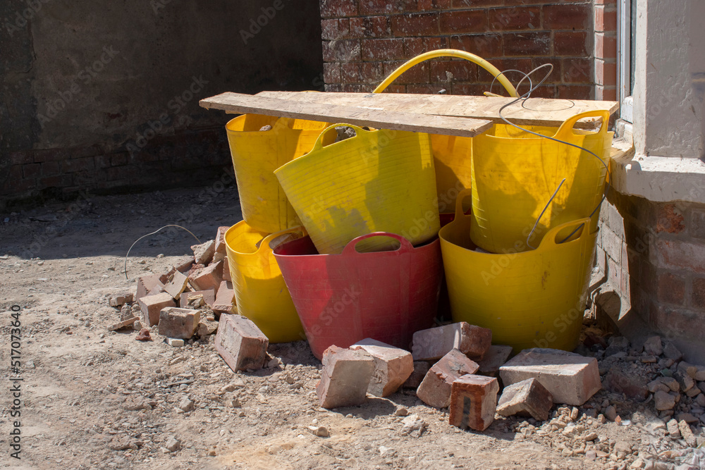 Yellow buckets and only one red covered with wooden planks. Work site materials.