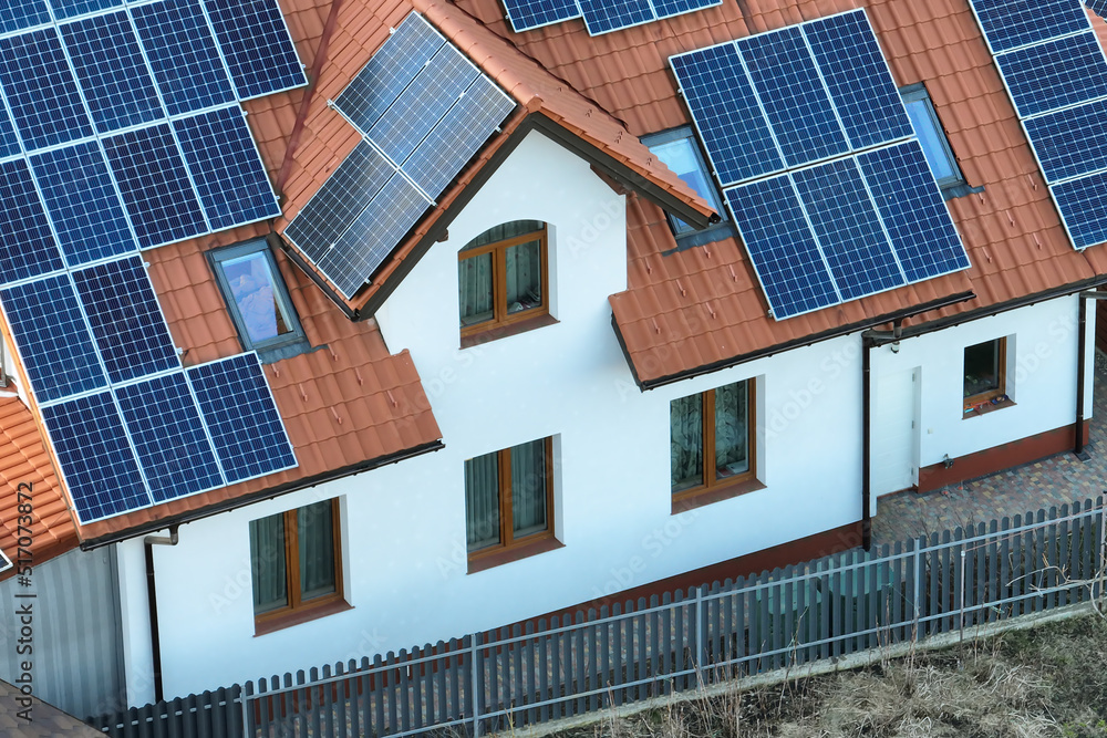 Fototapeta premium Residential house with rooftop covered with solar photovoltaic panels for producing of clean ecological electrical energy in suburban rural area. Concept of autonomous home