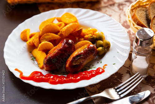 Roasted sausages served with baked potatoes and corn on white plate. High quality photo
