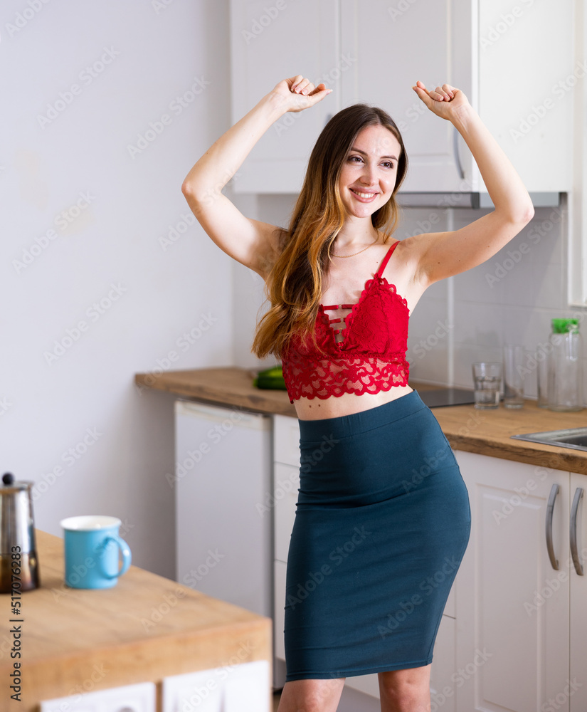 Relaxed attractive woman dancing at kitchen table at home.