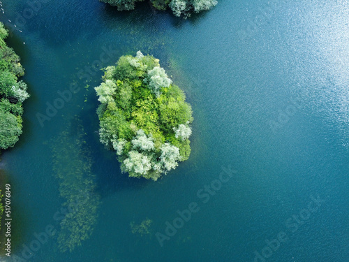Fototapeta Naklejka Na Ścianę i Meble -  Aerial down view of island on a tranquil clear water lake in Hertfordshire with underwater reeds