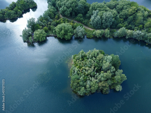 Aerial down view of 2 island on a tranquil clear water lake in Hertfordshire