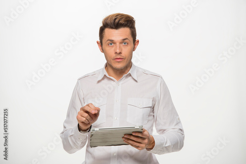 a man in a white shirt uses a tablet on a white isolated background.close-up portrait of a man with a tablet emotionally