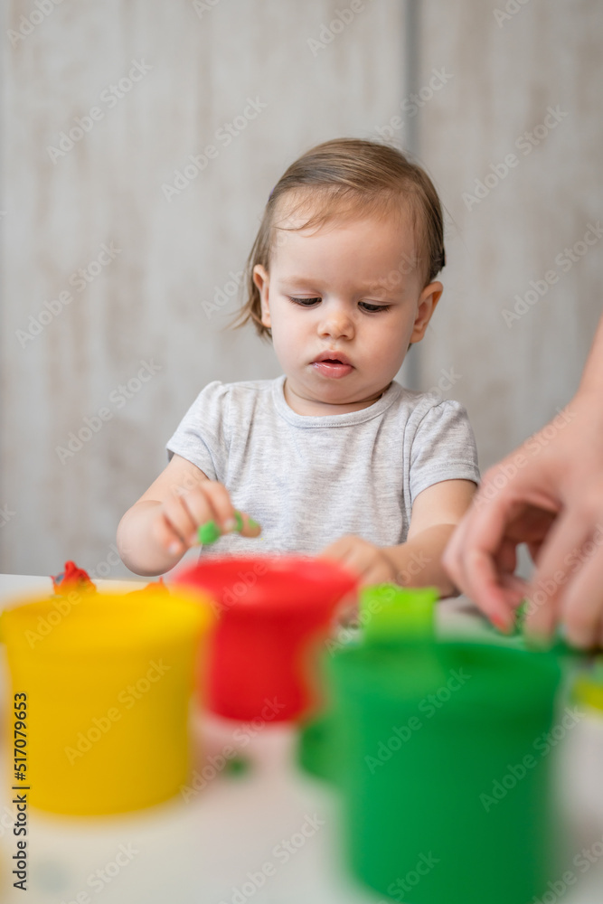One girl small caucasian toddler child playing with colorful plasticine on the table at home alone childhood and growing up development concept copy space One girl small caucasian toddler child playing with colorful plasticine on the table at home alone childhood and growing up development concept copy space