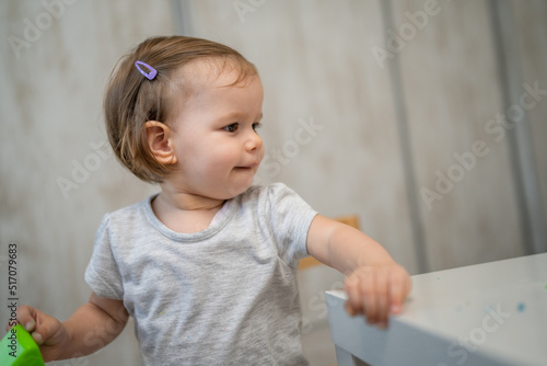 One small caucasian girl little female toddler playing at home in room alone looking to the side by the table copy space growing up and childhood concept copy space domestic life