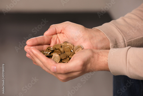 Closeup view of man holding coins indoors