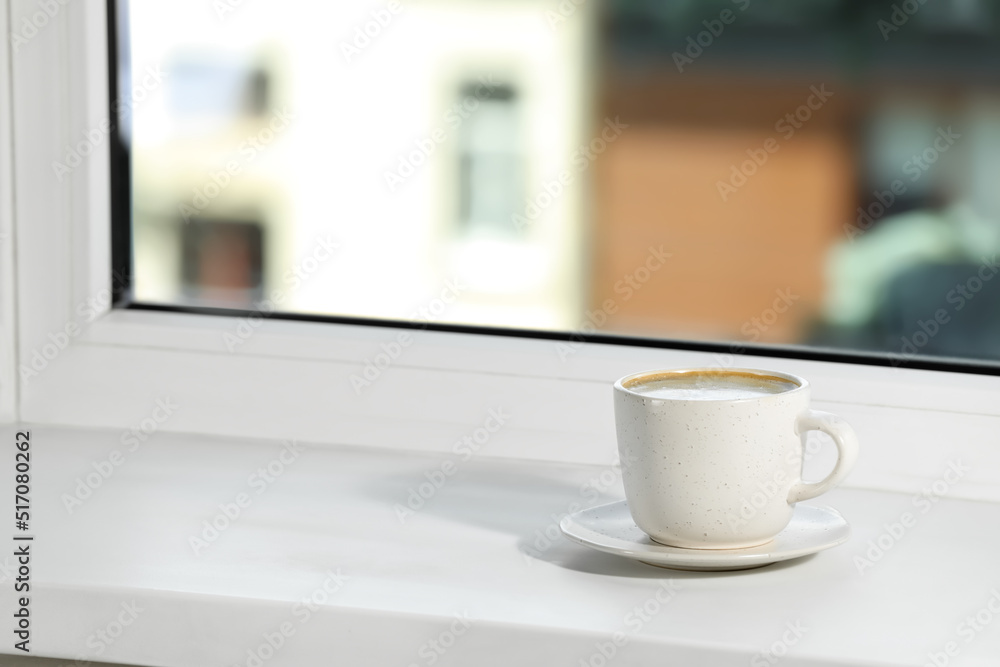 Cup of aromatic coffee on white sill near window indoors, space for text Cup of aromatic coffee on white sill near window indoors, space for text