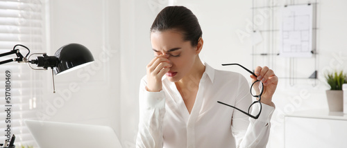 Stressed and tired young woman with headache at workplace. Banner design photo