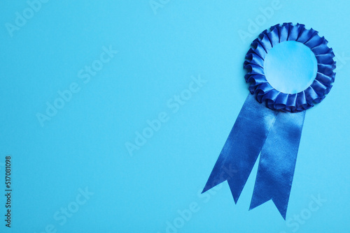 Blue award ribbon on turquoise background, top view. Space for text photo