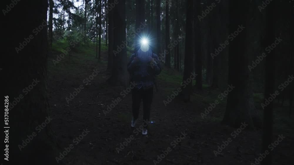 A tourist with a backpack and a head lamp walks through the night forest in the dark.Summer. Around the trees, branches. Slow motion 4k footage A tourist with a backpack and a head lamp walks through the night forest in the dark.Summer. Around the trees, branches. Slow motion 4k footage