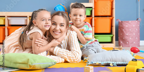 Nanny and cute little children in playroom