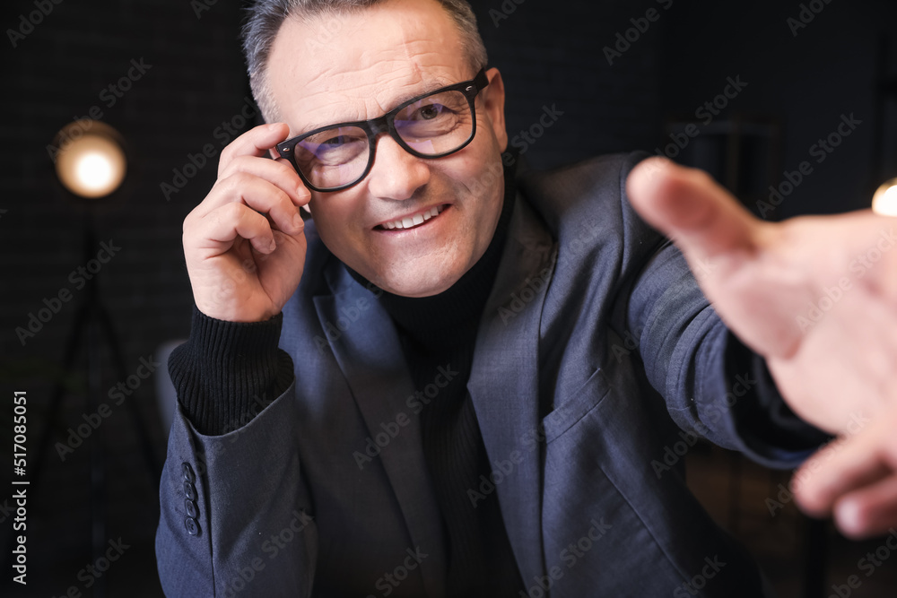Happy mature businessman video chatting in office at night Happy mature businessman video chatting in office at night