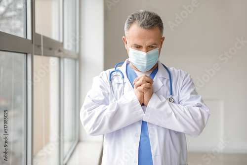 Praying mature male doctor ...