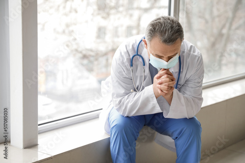 Praying mature male doctor ...