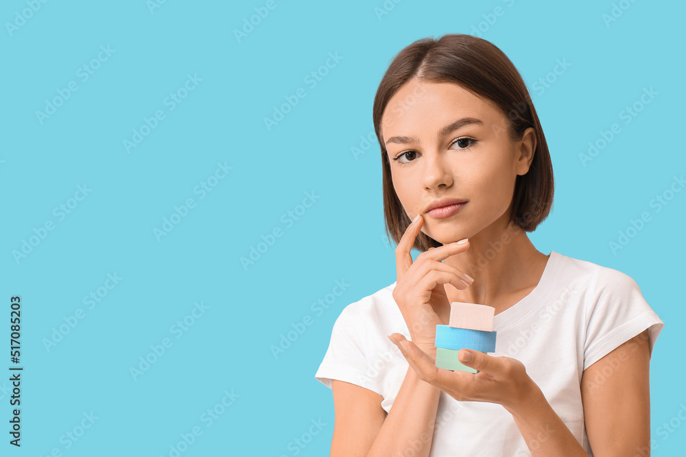 Pretty young woman with makeup sponges on blue background Pretty young woman with makeup sponges on blue background