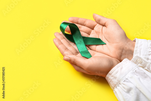 Wallpaper Mural Hands with green ribbon on yellow background. Liver cancer concept Torontodigital.ca