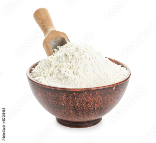 Bowl with wheat flour and scoop on white background