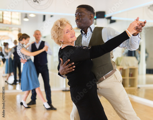 Fotografering Elderly woman learning ballroom dancing in pair in dance studio