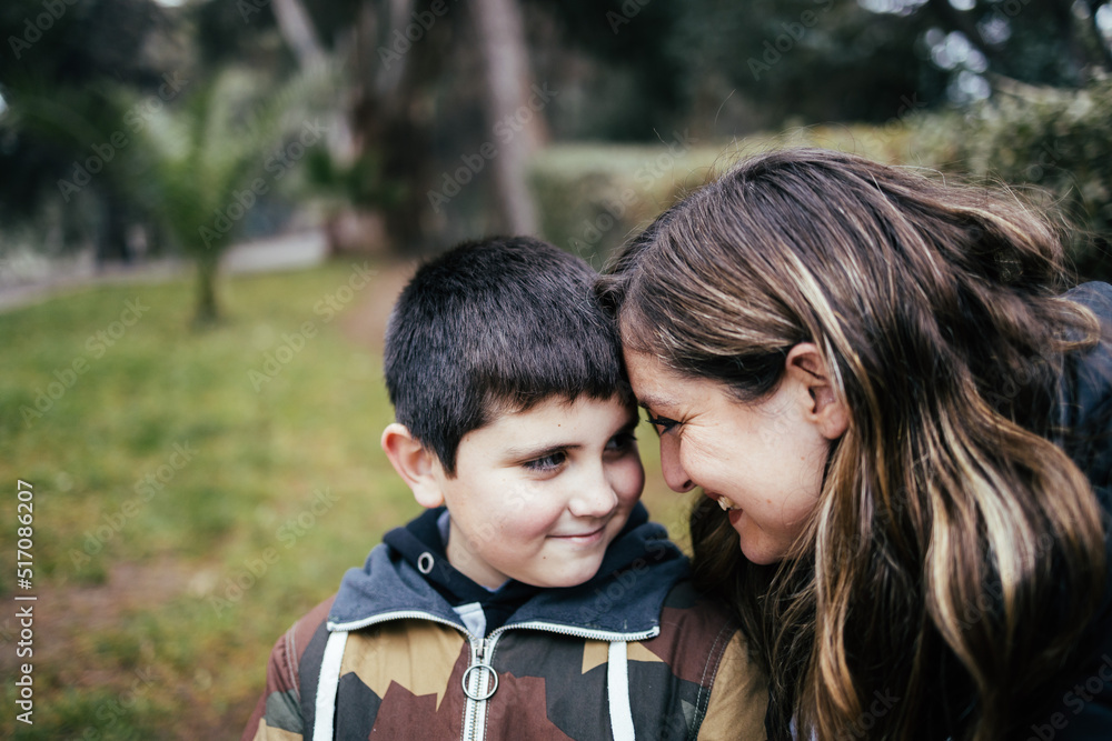 Young blonde latin mother hugging and laughing with her young son in the park. Single parent family Young blonde latin mother hugging and laughing with her young son in the park. Single parent family