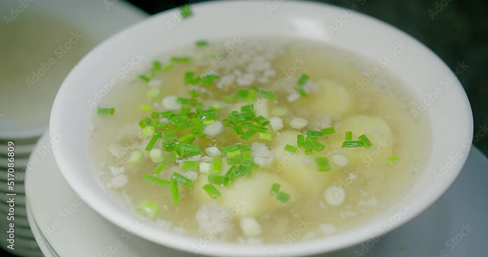 Close up person falling chopped spring onions into bowl of hot Clear Soup with Tofu and Minced Pork, Thai food Close up person falling chopped spring onions into bowl of hot Clear Soup with Tofu and Minced Pork, Thai food