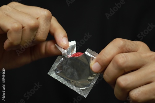 Ready-to-use condoms in male hand ,
concept on the bed Prevent infection.