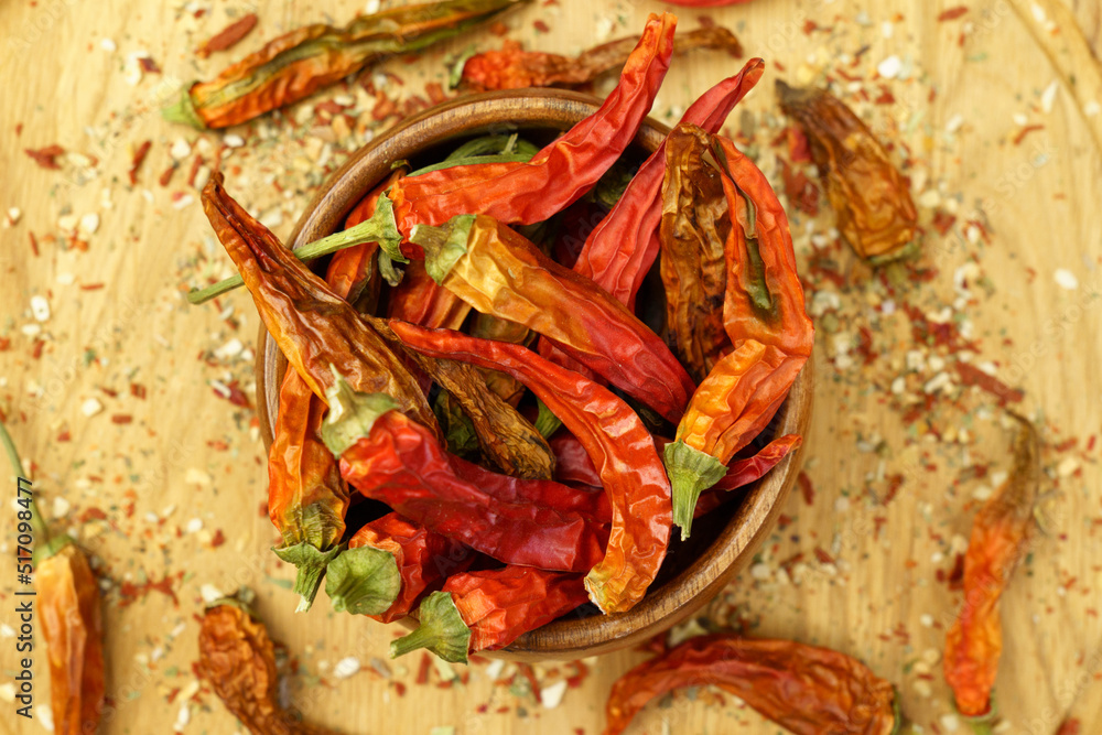 Chili peppers falling, spice seasoning, dried red peppers on a wooden table, background, dry paprika. Selective focus Chili peppers falling, spice seasoning, dried red peppers on a wooden table, background, dry paprika. Selective focus