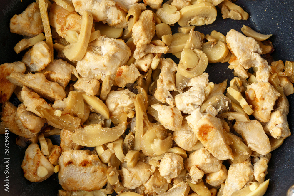 Chopped chicken fillet with mushroom fried on frying pan. Cooking process close up. Chopped chicken fillet with mushroom fried on frying pan. Cooking process close up.