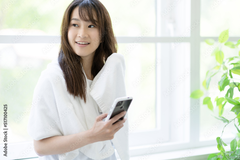 窓際で髪の毛を拭く女性