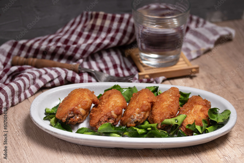 Herb fried chicken wings in white plate on wooden floor Herb fried chicken wings in white plate on wooden floor