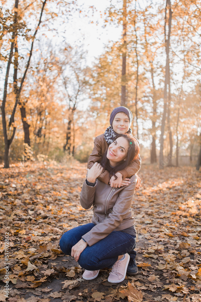 son with mom in autumn park with orange leaves