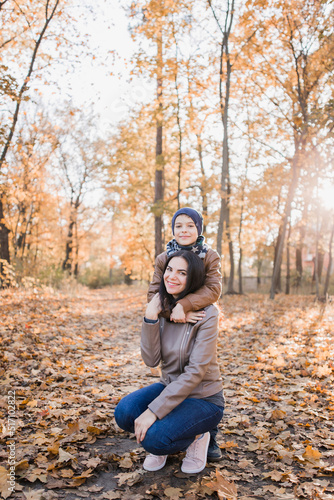 son with mom in autumn park with orange leaves © dyachenkopro