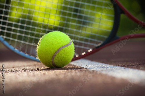 Yellow tennis ball near racquet and white line © NetPix