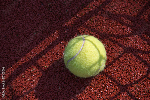 Shadows of net surrounding a tennis ball on court