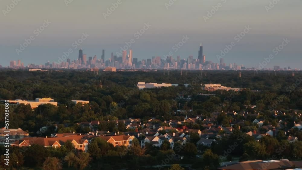 Aerial panorama of Chicago suburbs and Downtown Skyscrapers on the horizon, sunset warm light